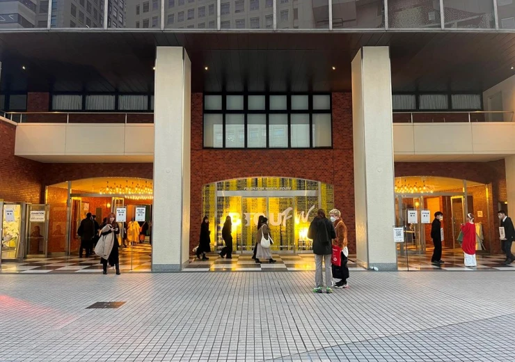 Vstup budovy Bunka Fashion Graduate University s procházejícími účastníky probíhajícího Fashion Weeku.
